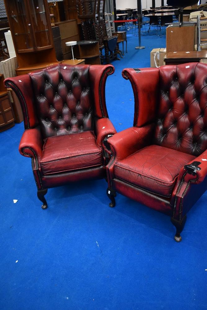 A pair of red leather button back wing armchairs