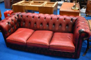 A red leather three seater button back chesterfield settee