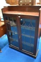 A late 19th or early 20th Century oak bookcase having shaped leaded glass doors, in the Art