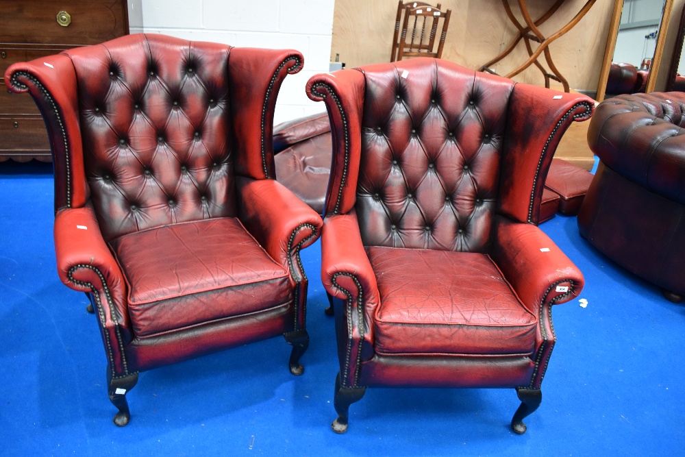 A pair of red leather button back wing armchairs