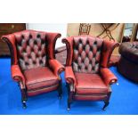 A pair of red leather button back wing armchairs