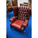 A red leather button back wing armchair