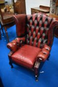 A red leather button back wing armchair