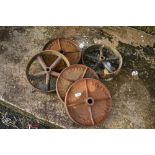 A selection of vintage cast iron wheels, from small cart , trough or similar