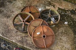 A selection of vintage cast iron wheels, from small cart , trough or similar