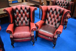 A pair of red leather button back wing armchairs