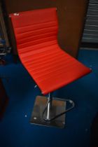 A modern kitchen bar stool, in chrome and red leather