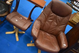 A brown leather swivel armchair and footstool on beech frame