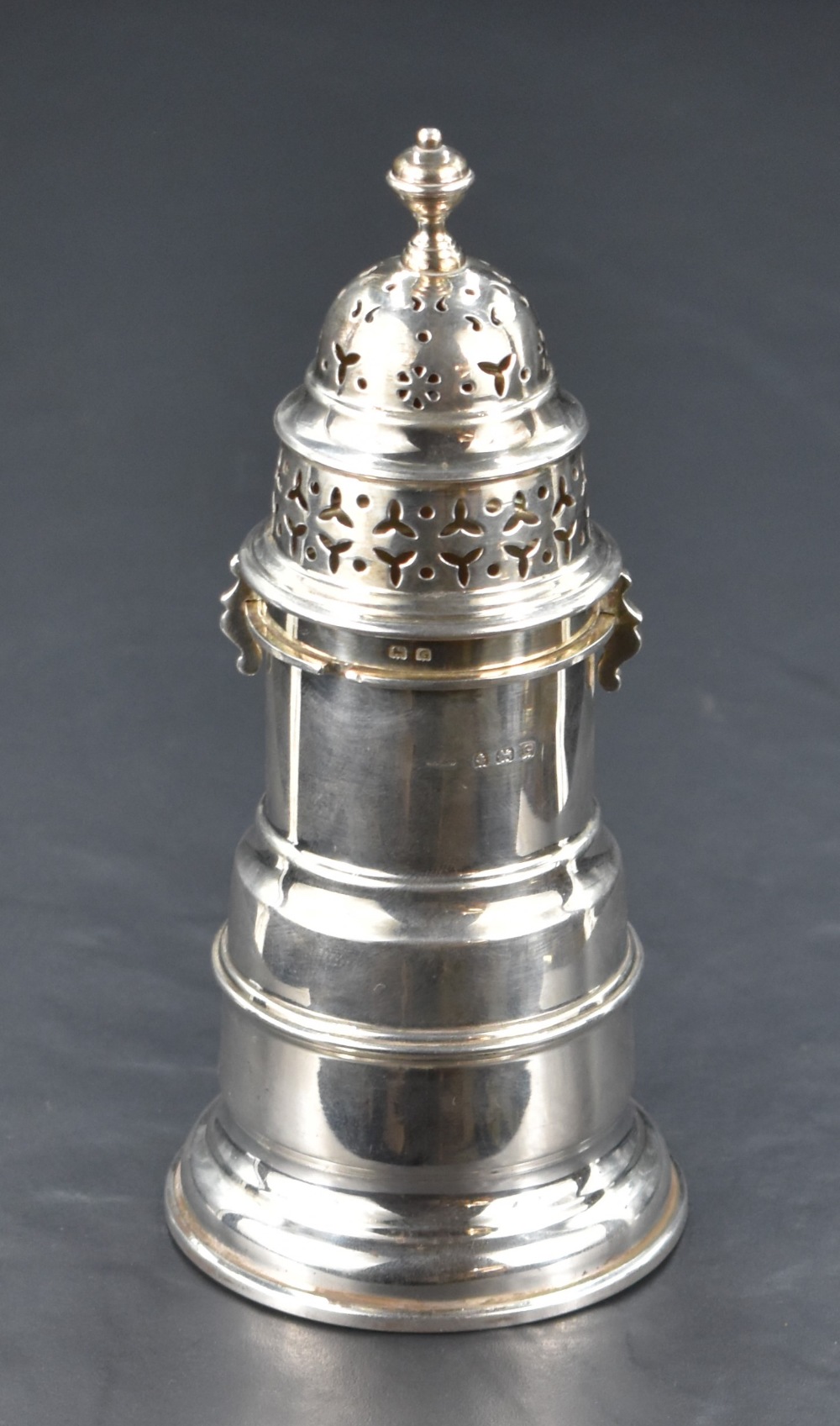 A George V silver sugar sifter, of traditional design with pierced finial topped twist-off cover