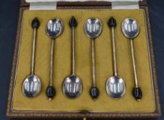 A cased set of six early 20th century silver coffee spoons, each with a black 'coffee bean' at the