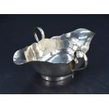 A George V silver double spouted and handled sauce boat, having a shaped rim and applied loop