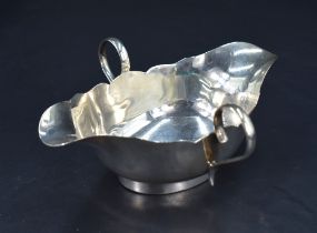 A George V silver double spouted and handled sauce boat, having a shaped rim and applied loop