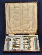 A cased set of eight silver plated coffee spoons with yellow coffee beans to the terminals with