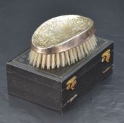 A Queen Elizabeth II silver mounted clothes brush, of concaved oval form with foliate scroll