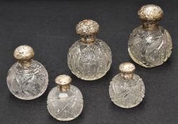 A collection of five silver mounted cut glass scent bottles of various size and design, three having