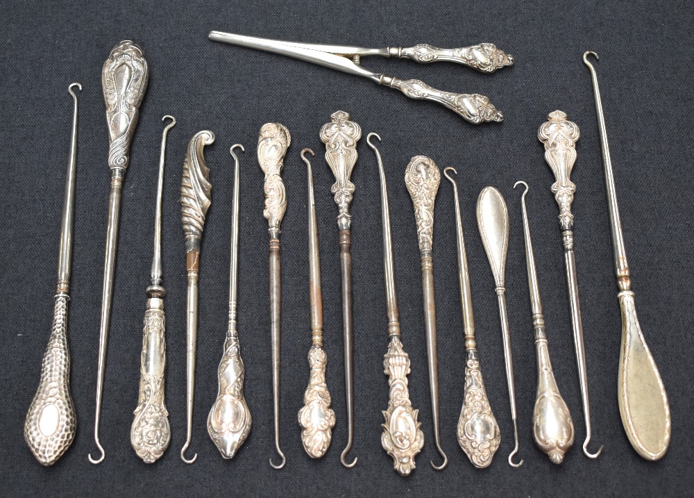 A collection of fifteen silver and white metal handled button hooks of various size and design