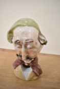 A continental porcelain figural ashtray, in the form of an old man with moustache, measuring 13cm