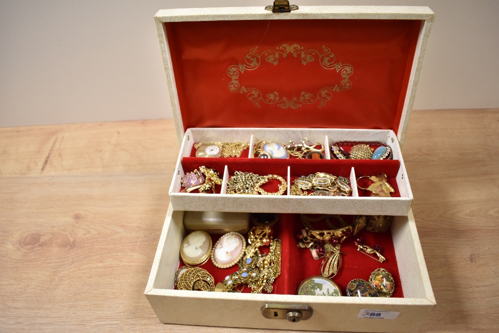 A multi-tier jewellery box containing an assortment of yellow metal jewellery including a ladies