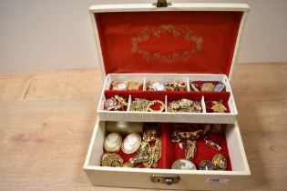 A multi-tier jewellery box containing an assortment of yellow metal jewellery including a ladies