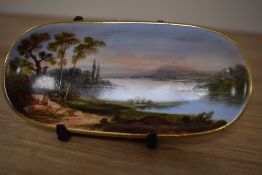 A 19th Century continental porcelain trinket dish, of elongated form, decorated with a sunlit lake