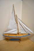 An early to mid 20th century painted wooden pond yacht, with sails, measuring 54cm long.
