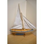 An early to mid 20th century painted wooden pond yacht, with sails, measuring 54cm long.