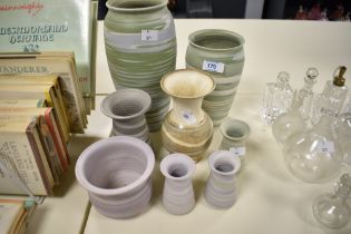 A collection of studio pottery, having matte finishes in lilacs, greens a beige.