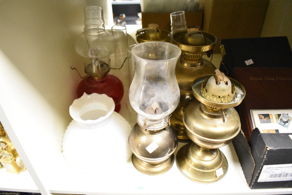 A collection of oil lamps, glass shades and chimneys.