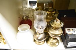 A collection of oil lamps, glass shades and chimneys.