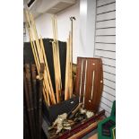 A collection of vintage pool cues, an antique score board and a slection of pockets.