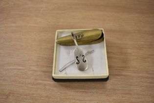 A novelty white metal cello with bow, measuring 6cm long, contained within a yellow metal case