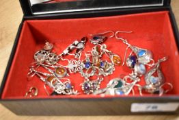 A decorative floral jewellery box containing an assortment of predominantly silver earrings, some