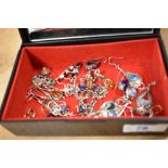 A decorative floral jewellery box containing an assortment of predominantly silver earrings, some
