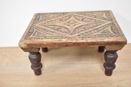 A late 19th Century oak carved stool, of rectangular form and raised on four turned supports,