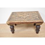 A late 19th Century oak carved stool, of rectangular form and raised on four turned supports,