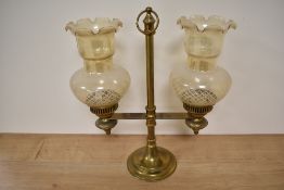 A Victorian brass two candle holder with glass shades, measuring 40cm tall