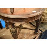 An early 20th Century oak circular coffee table having carved friese and cup and cover legs with