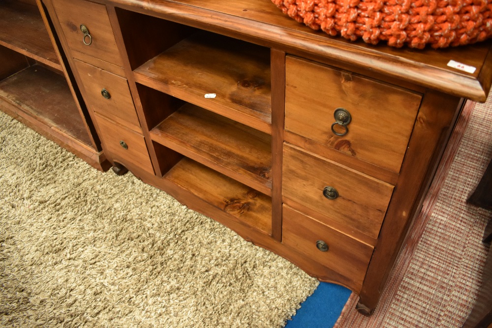 A modern hardwood TV cabinet or small sideboard, having central open shelves flanked by two banks of