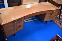 A vintage teak dressing table of curved form, width approx. 163cm, mirrors have been removed but are