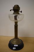 A vintage oil lamp having wheel cut glass reservoir, reeded-column and black ceramic base.