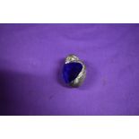 A white metal pincushion in the form of a chick, having iridescent blue/cerise velvet to top.