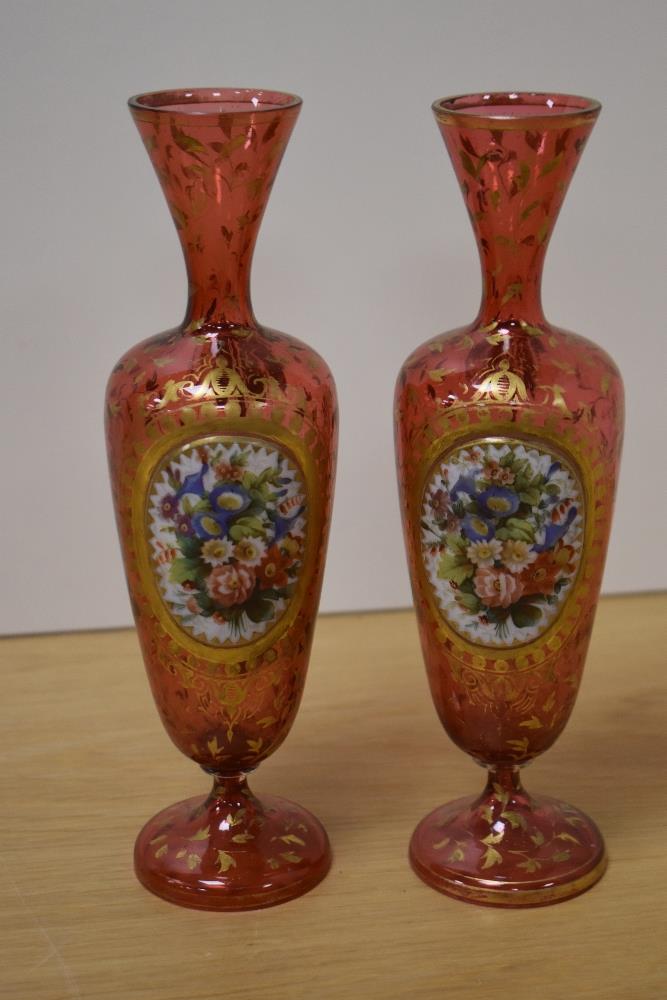 A pair of late 19th/early 20th Century Bohemian glass vases, decorated with vignettes of floral