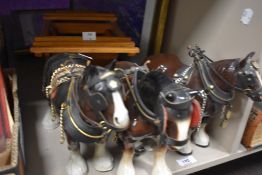 Three ceramic Shire Horse studies sold along with a wooden cart.
