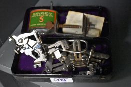 A vintage Singer sewing machine tin, containing a selection of Singer sewing machine attachments,