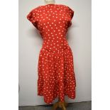 A 1950's red dress, having white polka dot pattern, tiered skirt and rear metal zip, larger size.