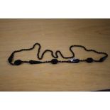 A statement necklace of geometrically carved black stone with alternating teardrop and rectangular