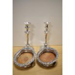 A pair of silver plated candlesticks and two unusual champagne or spirit coasters, having later