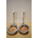 A pair of silver plated candlesticks and two unusual champagne or spirit coasters, having later