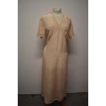 A 1930s / 1940s peach nightdress with lace and appliqué detail to bodice and tie fastening to waist,