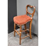 A Victorian correction chair of mixed woods, having balloon and rail back, with later upholstered